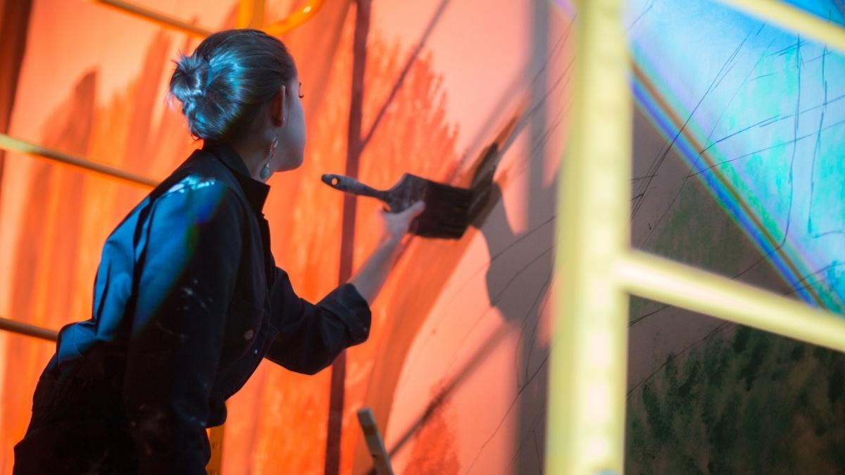 Woman painting mural on set.